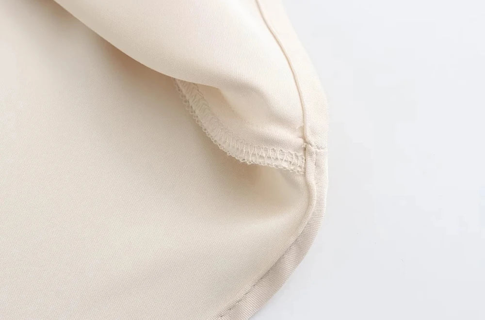 Detail view of the smooth satin texture and flowing hemline.