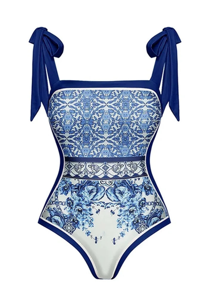 Blue and white patterned swimsuit with bow straps on a white background