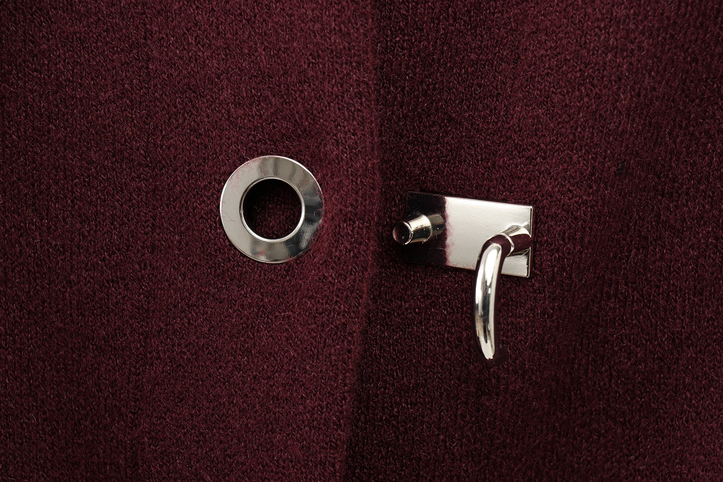 Close-up of a silver lock button on a burgundy cape