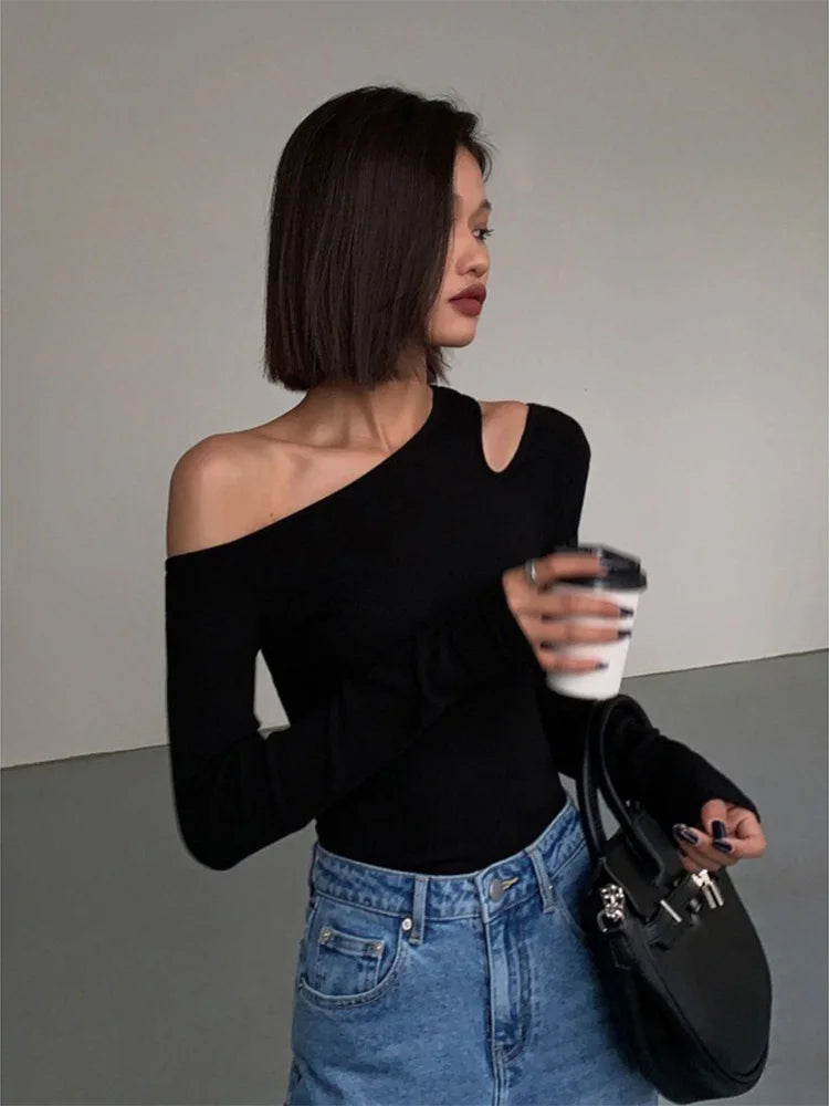 Model in the black asymmetric off-shoulder top, holding a coffee cup, exuding a relaxed and stylish vibe.