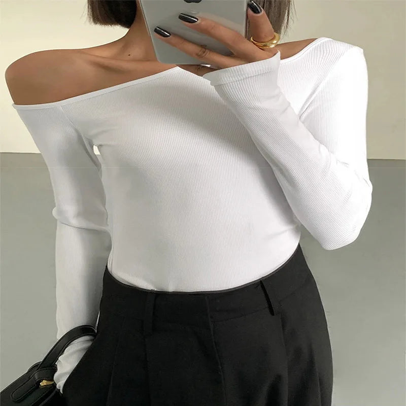 Model wearing the white variant of the asymmetric off-shoulder top, highlighting its elegance and versatility.