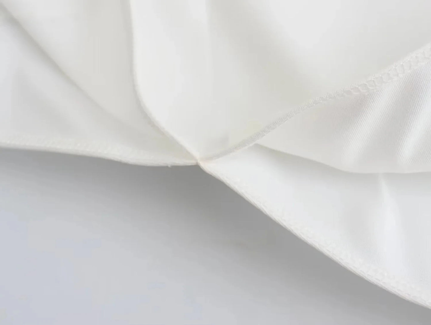 Close-up of the high-quality sewing and stitching on the side of the asymmetrical skew collar t-shirt