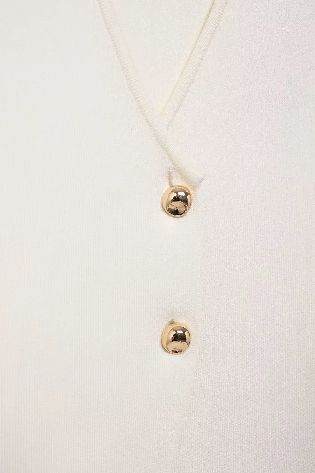 Front view of a white basic knit top featuring gold button detailing zoom in
