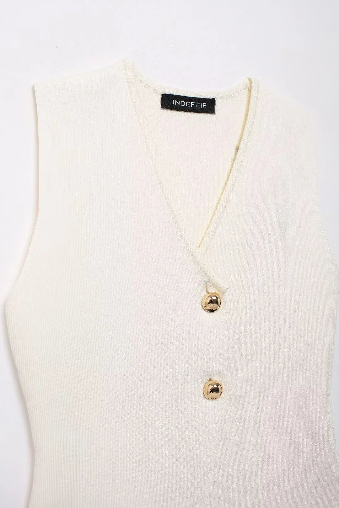 Front view of a white basic knit top featuring gold button detailing.