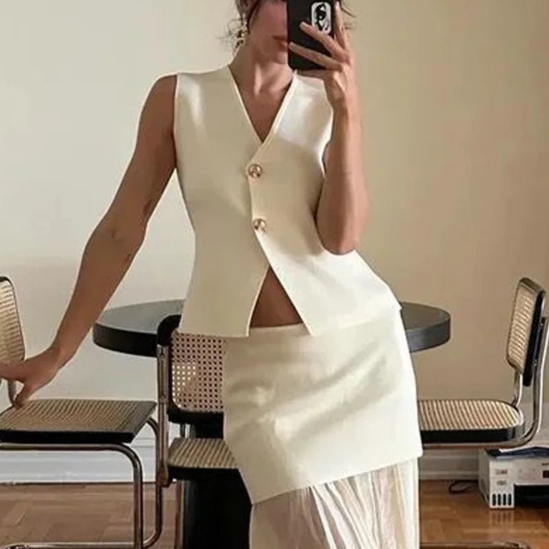 Model taking a mirror picture of the white basic knit top with gold buttons, styled for a chic look."