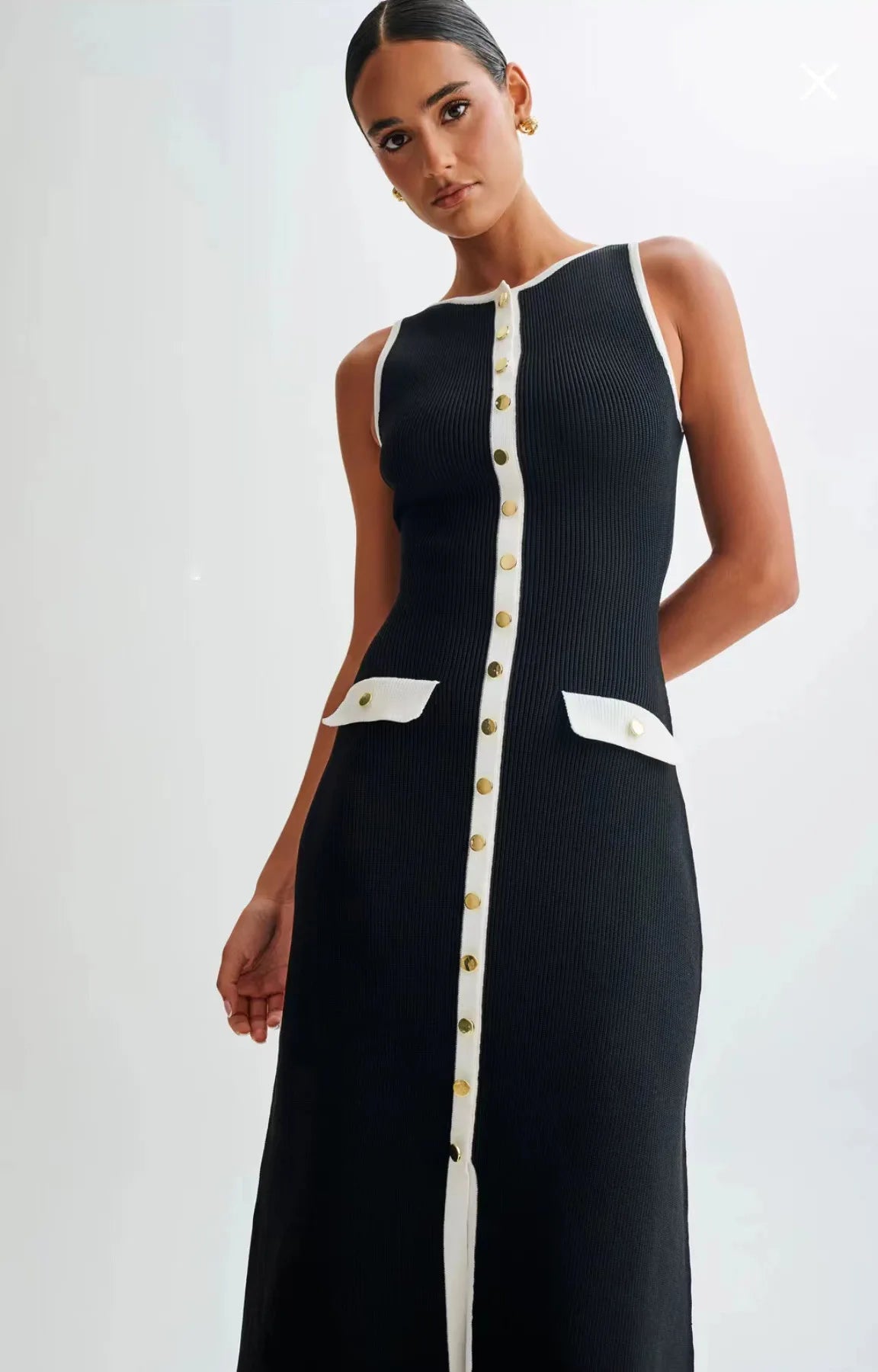 Model wearing the black knitted mid-calf dress, looking down toward the camera, capturing a stylish and elegant pose.
