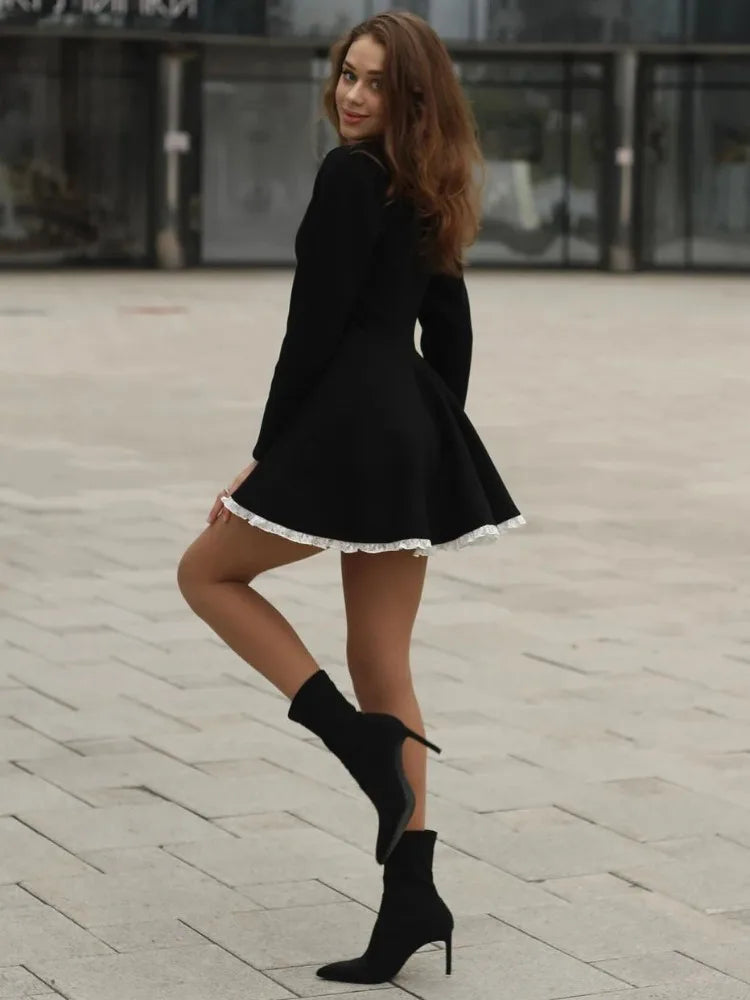 Right side view of the model wearing the black lace mini dress, emphasizing the lace pattern and form.