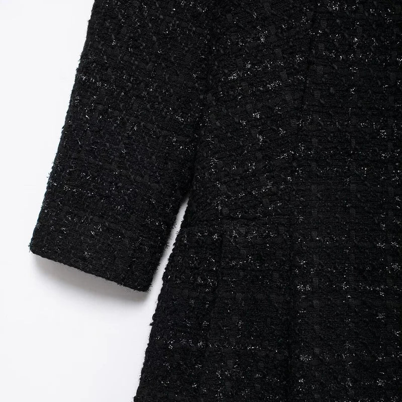 Black tweed dress with a loose fit and textured fabric, embodying sophistication and modern design.