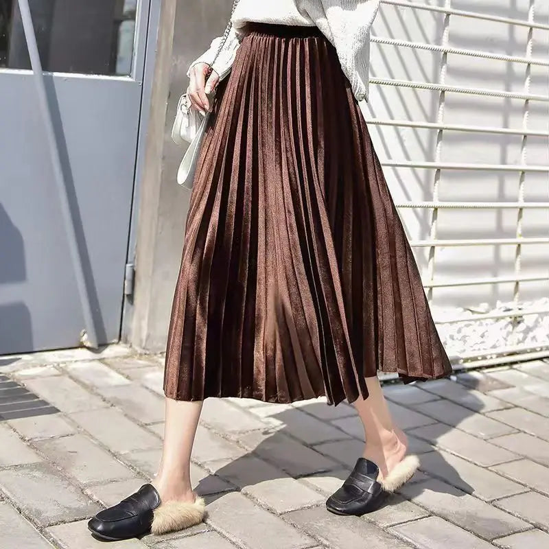 Rich brown pleated velvet midi skirt designed with an elastic waist and flowing pleats, ideal for seasonal elegance.