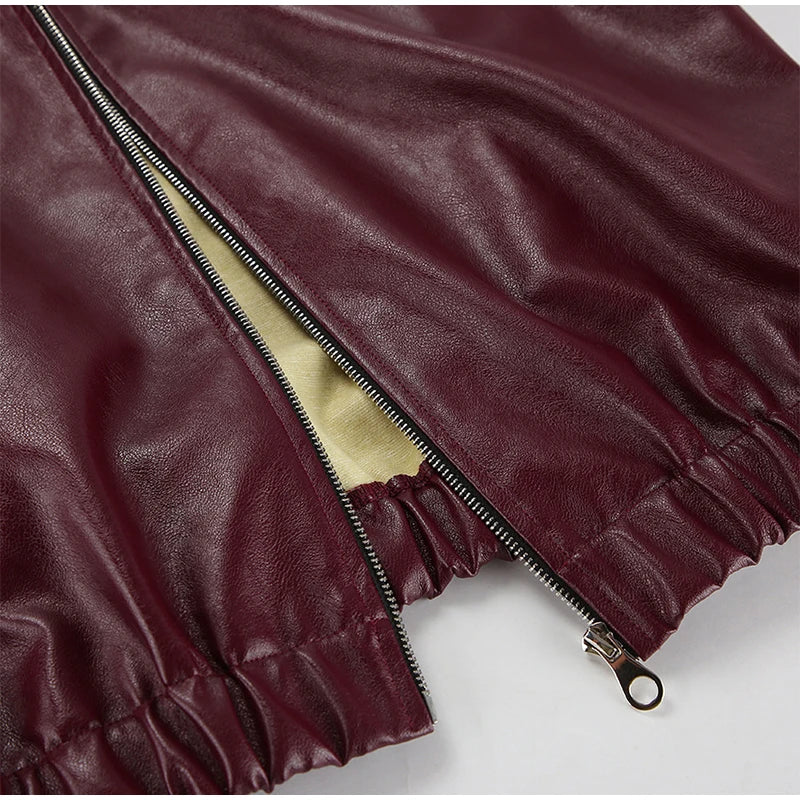 Close-up view of the hem of the burgundy faux leather jacket, showing precise detailing and quality finish