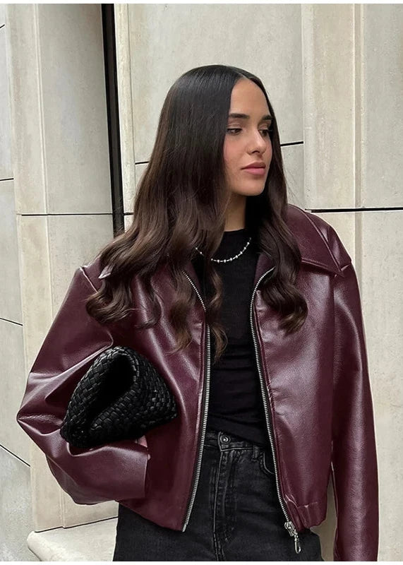 Side profile of the model wearing a burgundy faux leather jacket, highlighting the jacket’s silhouette.