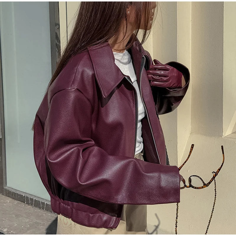 Side view of the model wearing a burgundy faux leather jacket, highlighting the jacket's structured fit and sleek silhouette.