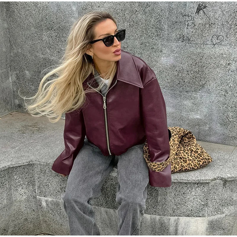 Model sitting in a burgundy faux leather jacket, styled casually for a modern and laid-back look.