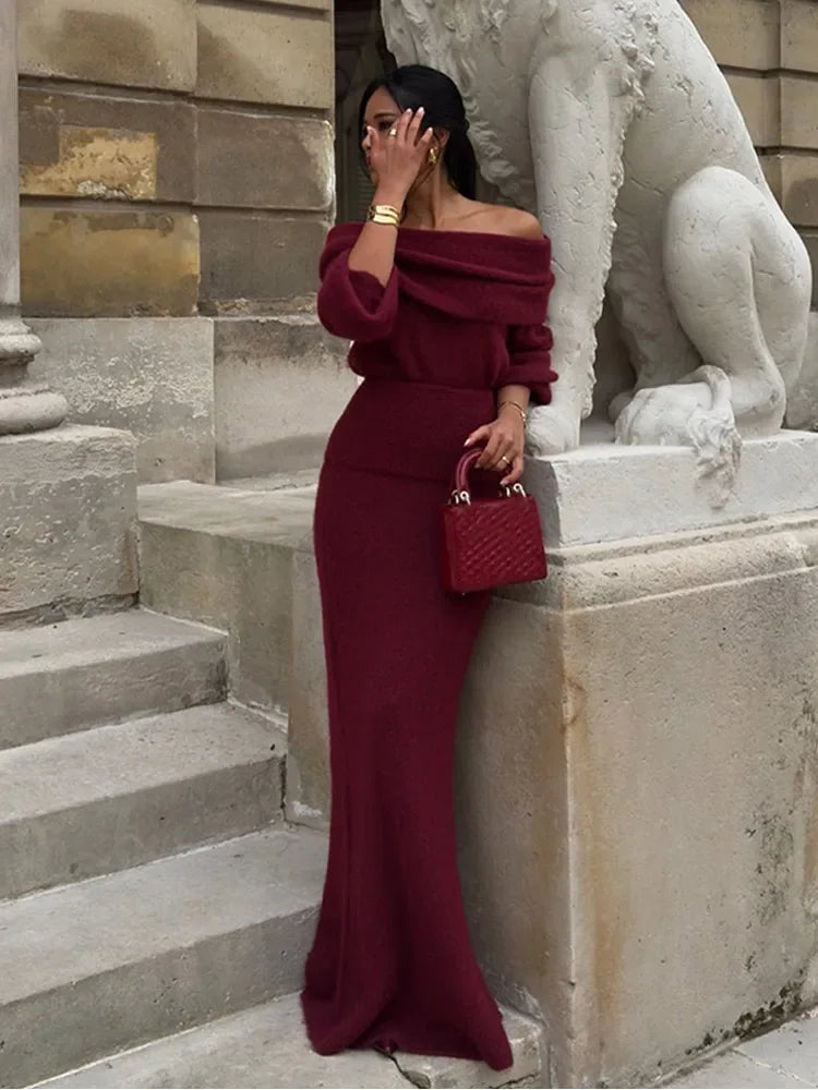 Model wearing Burgundy off-shoulder knitted maxi dress, looking to the side with a chic pose.