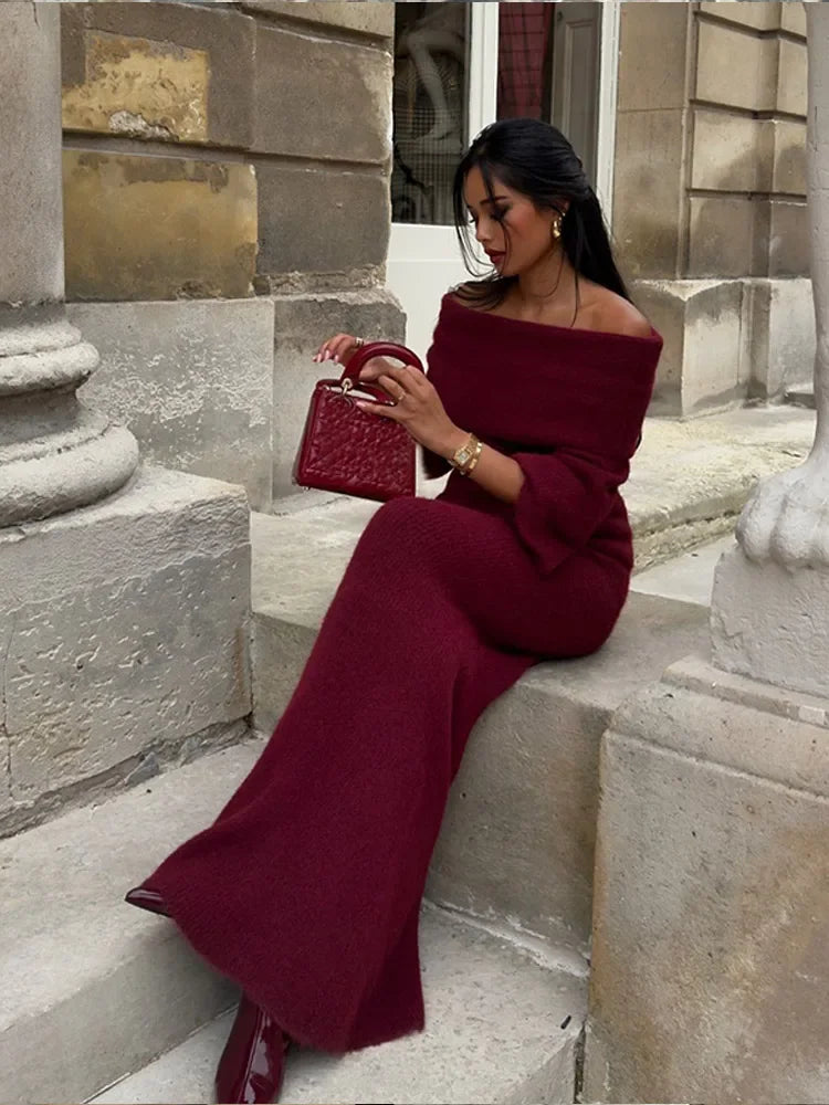 Model sitting in the Burgundy off-shoulder knitted maxi dress with a relaxed, stylish look.