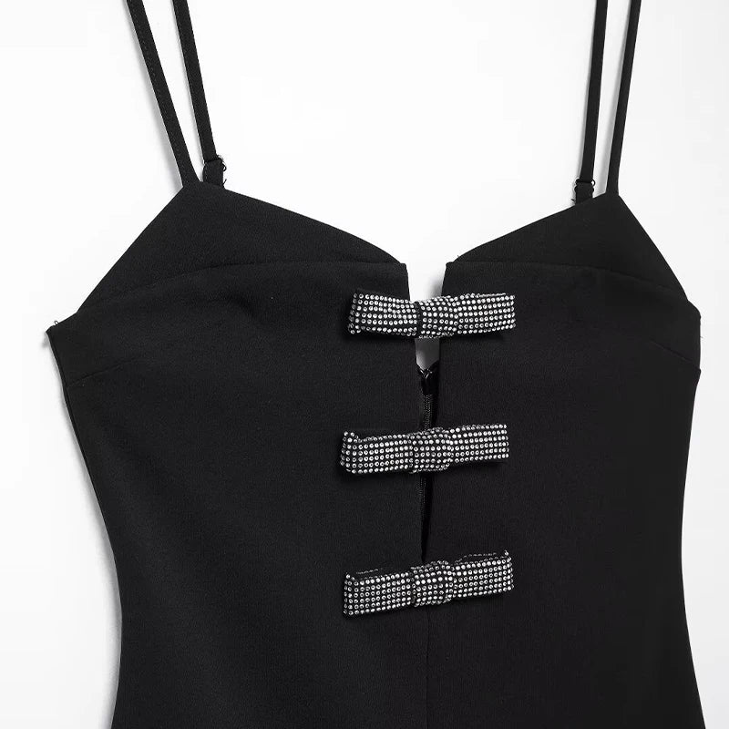 Close-up of the three sparkling diamond-encrusted bows on black V-neck mini dress.