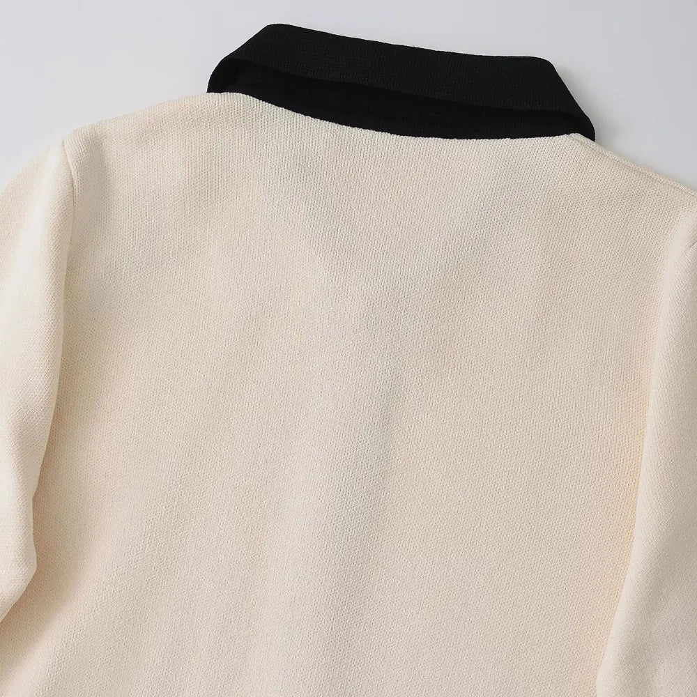 Luxurious knitted mini dress design with gold button highlights, black contrast details, and cream beige fabric