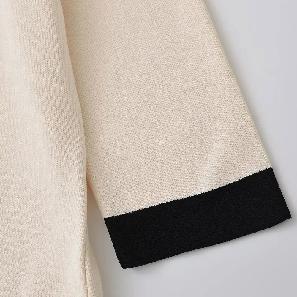 Detailed view of a knitted mini dress featuring cream beige tones, black accents, and luxurious gold button embellishments