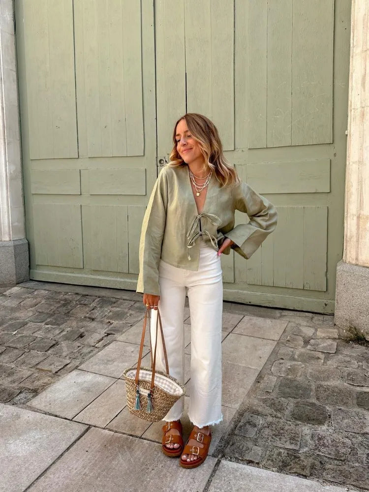Green linen blouse with lace-up design, balancing elegance and casual style.