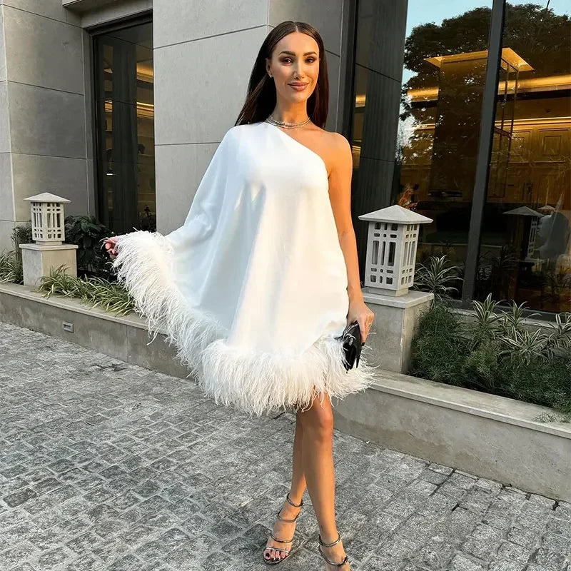 Party-ready white one-shoulder mini dress with striking feather accents for a bold statement.