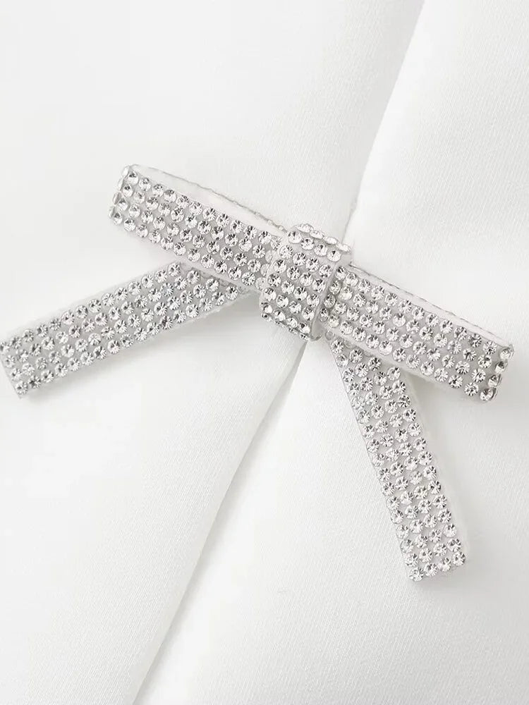 Side view of white halter neck top with backless cut and diamond bow for an elegant style.