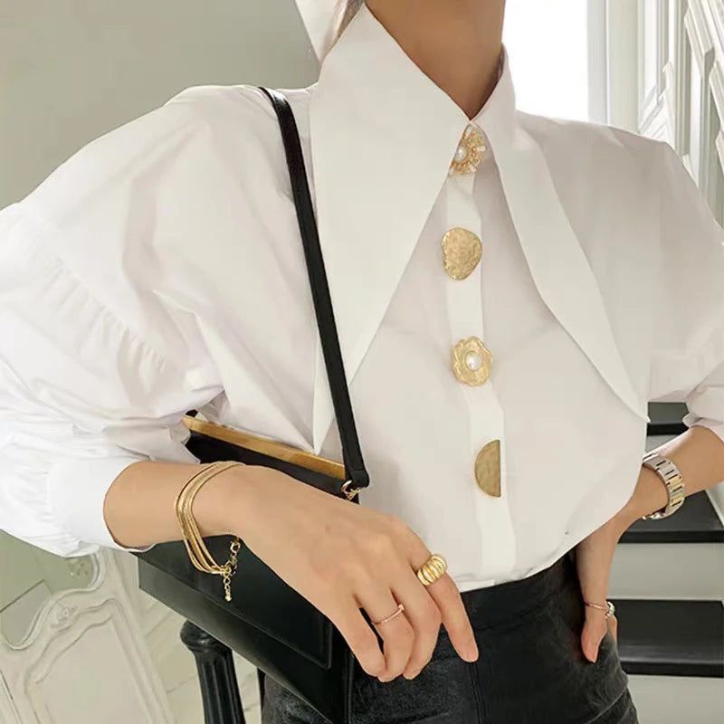 Close-up shot of the gold pearl buttons on the white blouse with a long collar for a refined look.