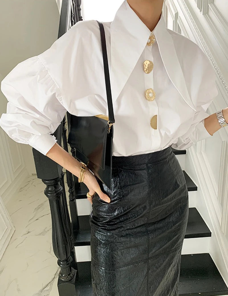 Full view of the stylish white blouse featuring a long collar and elegant gold pearl buttons.
