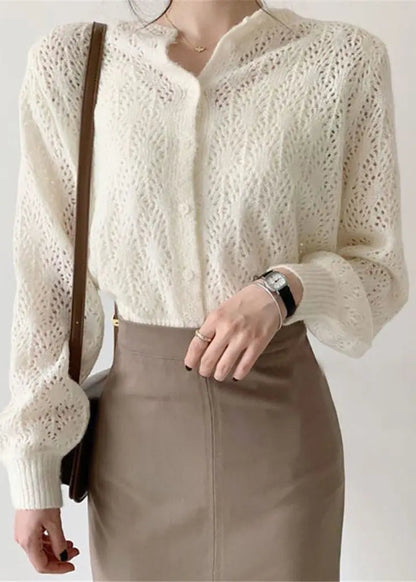 A person wearing a button-down crochet cardigan in a solid color, with a light-colored shirt and a brown skirt.
