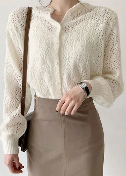 A person wearing a button-down crochet cardigan in a solid color, with a light-colored shirt and a brown skirt.