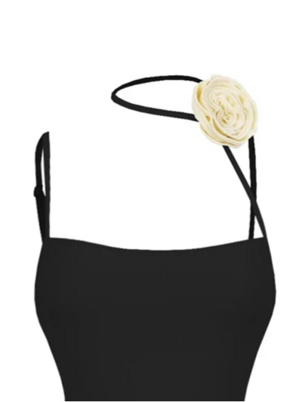 Black swimsuit with ruched design and fringes on a white background