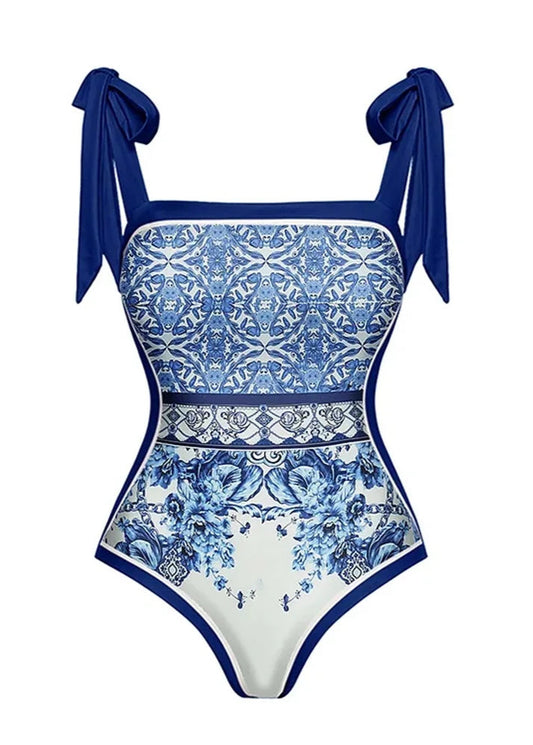 Blue and white patterned swimsuit with bow straps on a white background