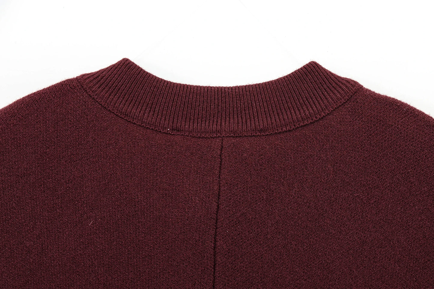 Close-up of a burgundy cape with a ribbed neckline on a white background