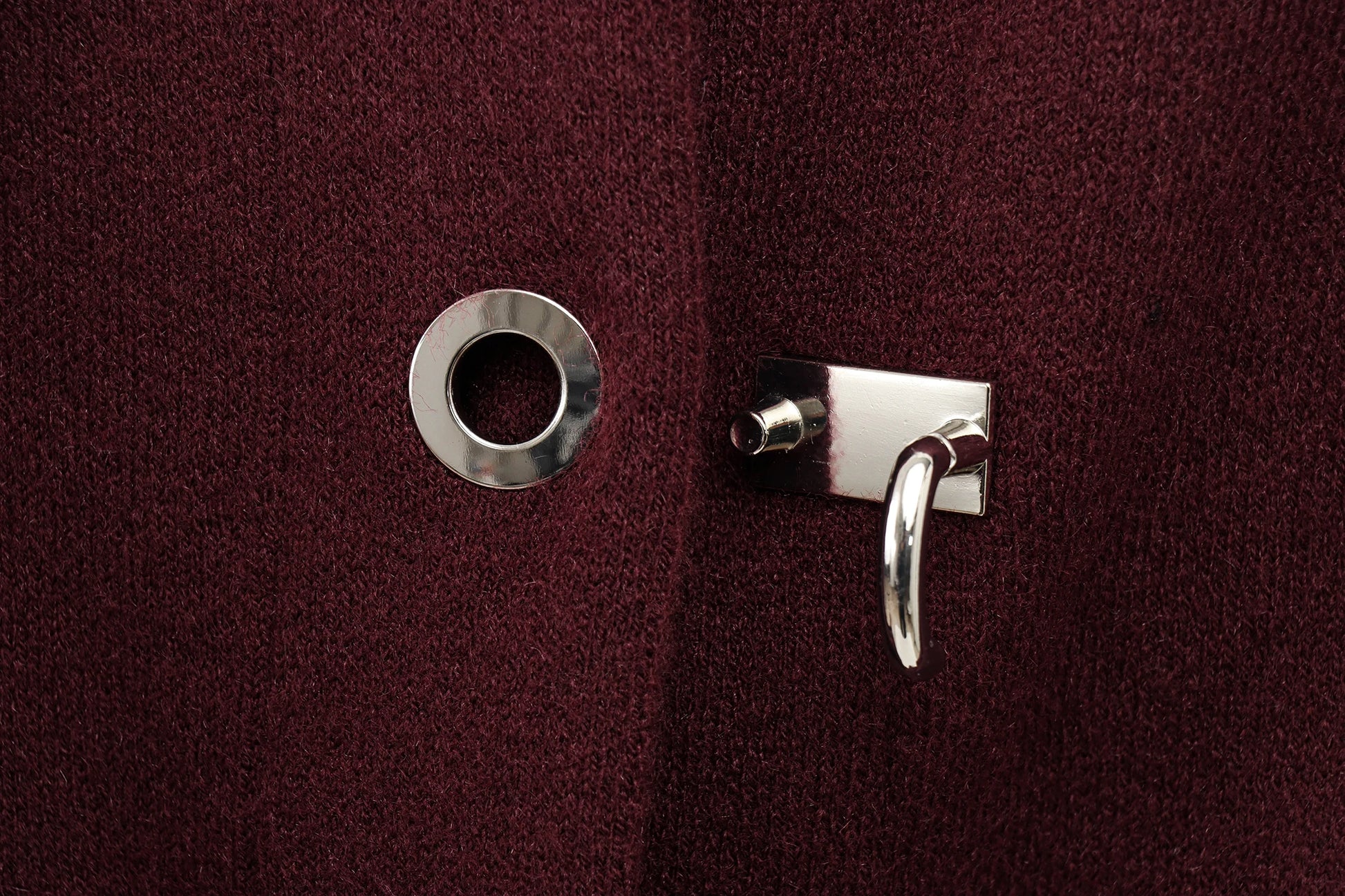 Close-up of a silver lock button on a burgundy cape