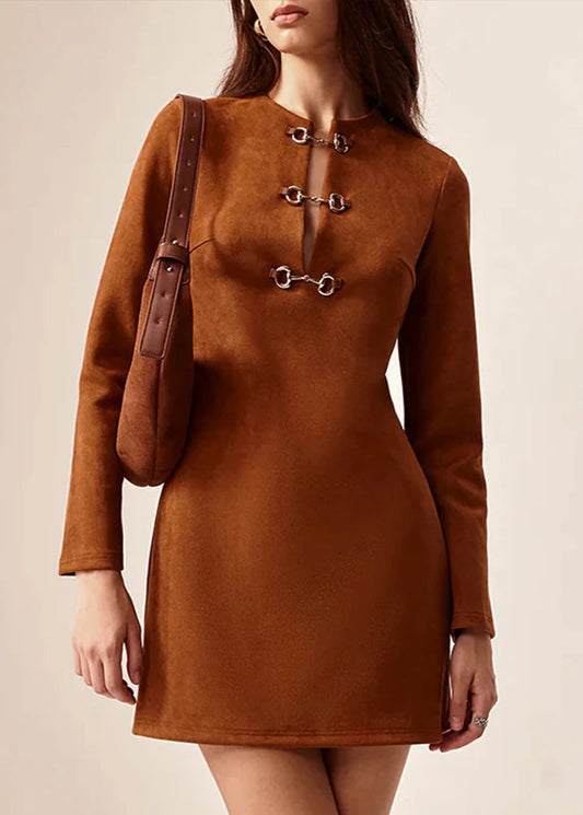 A woman wearing a brown mini dress with hollow out button details and a round neckline, with a back zipper closure and gold hardware.